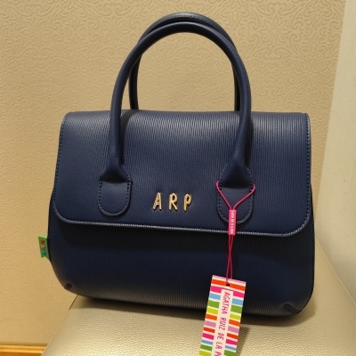 Mala azul escura com letras douradas ARP e etiqueta colorida pendurada