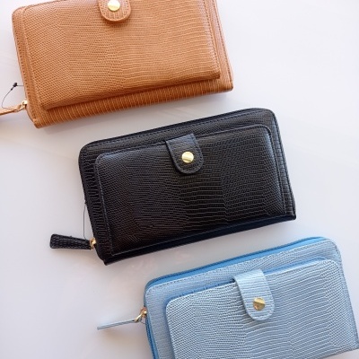 Três carteiras texturizadas castanho claro, preto e azul claro com fecho de pressão dourado.