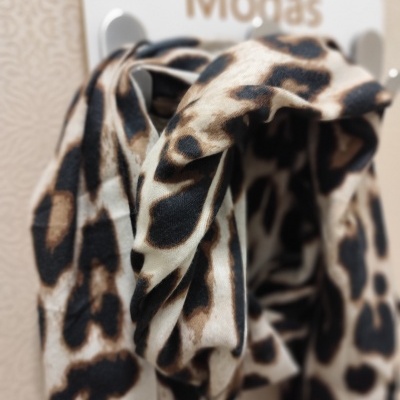 Lenço ou echarpe com padrão animal em bege, castanho e preto pendurado