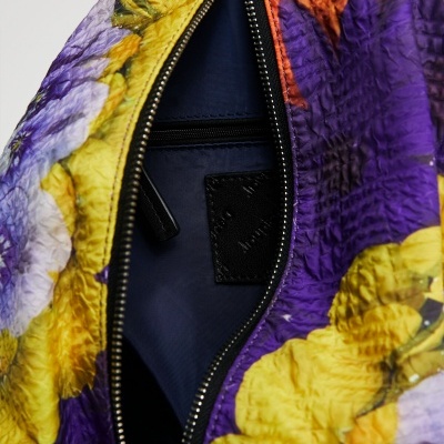 Mochila com padrão floral colorido e zíper aberto mostrando interior azul escuro