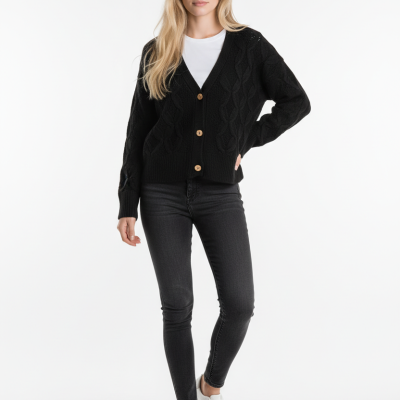 Modelo com cárdigan preto de malha, jeans pretos e ténis brancos