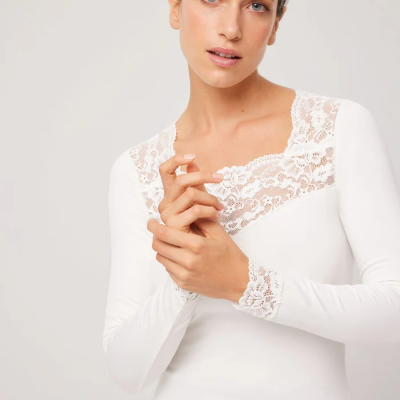 Mulher com camisola branca de manga comprida com renda floral no decote e punhos