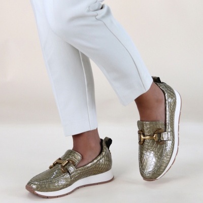 Sapatilhas verdes metalizadas com padrão de crocodilo e detalhe dourado usadas com calças brancas