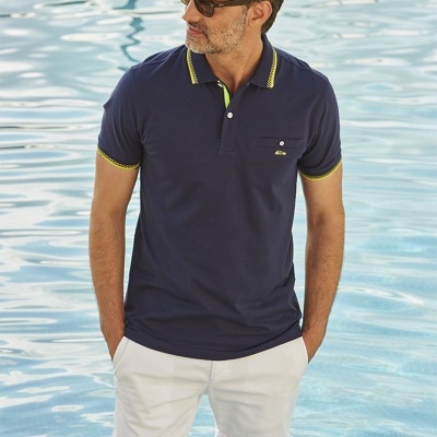 Homem com polo azul escuro e calções brancos de pé numa piscina.