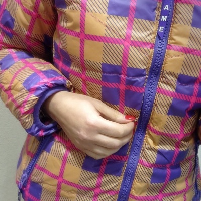 Casaco acolchoado castanho, roxo e rosa com fecho de correr roxo e etiqueta PAME