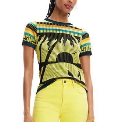 Mulher veste t-shirt de malha com padrão de palmeiras coloridas e calças amarelas.