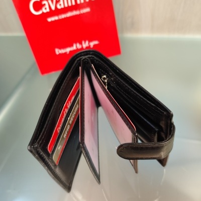 Carteira preta de couro aberta com cartões e embalagem vermelha ao fundo