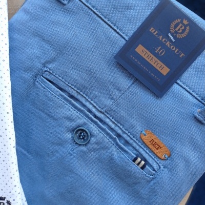 Calças masculinas azuis com etiqueta preta e detalhe de botão preto