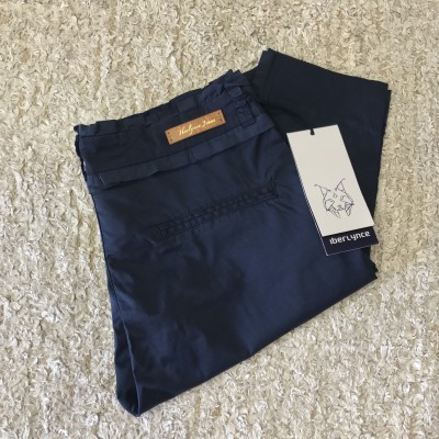 Calças azuis escuras com etiquetas visíveis sobre tapete bege