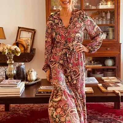 Vestido longo floral colorido com mangas compridas e decote em V usado em ambiente interior rústico