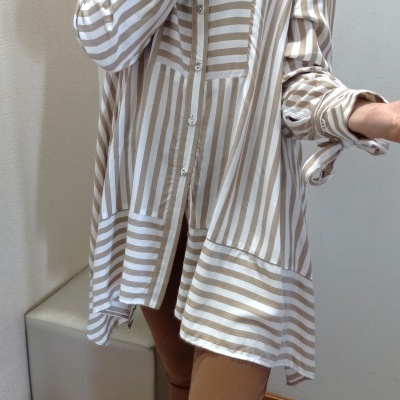 Camisa comprida riscada bege e branco com calças castanhas e sapatilhas brancas