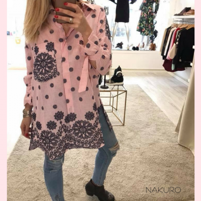 Camisa rosa com riscas brancas, flores e bolinhas pretas usada com jeans e botas em loja de roupa