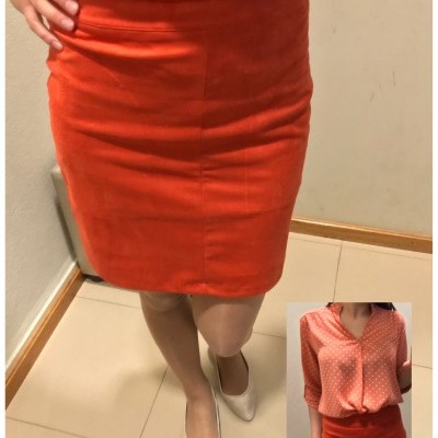 Mulher vestindo saia laranja e blusa cor de coral com bolinhas brancas