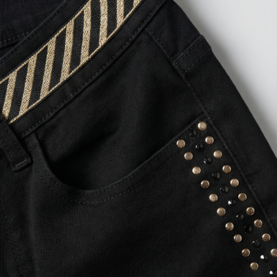 Calças pretas com bolso, cinto preto e dourado e tachas na lateral do bolso