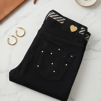 Calças pretas com decoração de tachas, brincos, carteira castanha e prato com alianças