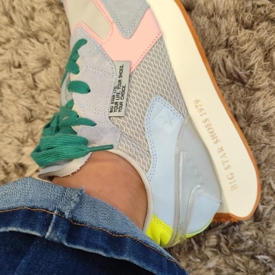 Tênis colorido BIG STAR com sola branca e detalhes variados, calçado em pé com jeans azul