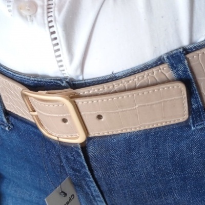 Cinto bege com padrão crocodilo em jeans azuis e camisa branca