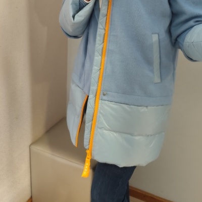 Casaco azul claro com fecho amarelo e pormenores acolchoados