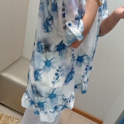 Blusa feminina transparente com padrão floral azul e branco, mangas dobradas, folhos na bainha