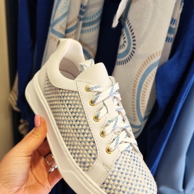 Ténis branco com padrão entrelaçado azul e bege e atacadores brancos com detalhes azuis