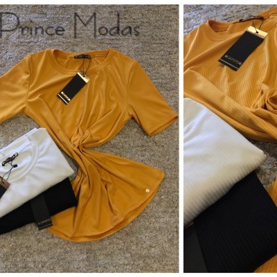 Três t-shirts caneladas nas cores mostarda, branca e preta com etiquetas pretas sobre tapete claro