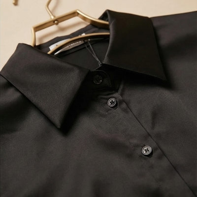 Camisa preta com botões e gola num cabide dourado