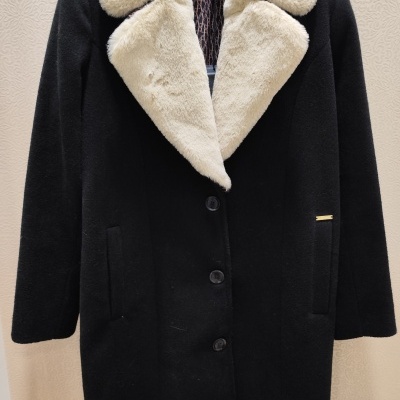 Casaco preto com gola em pelo sintético branco pendurado em cabide