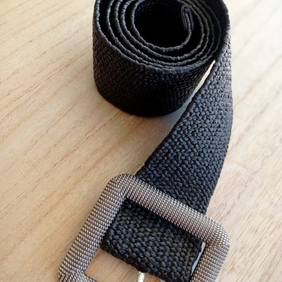 Cinto preto de tecido com fivela quadrada prateada sobre madeira clara