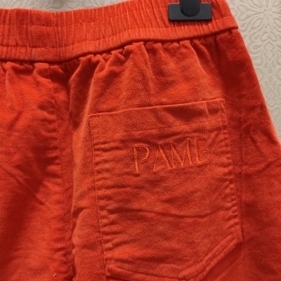 Calças ou calções laranja com bolso bordado e cabide preto