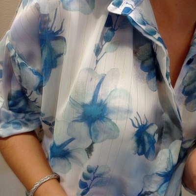 Blusa feminina azul e branca com padrão floral e gola