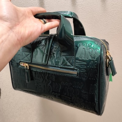 Mala de mão verde escuro brilhante com textura em relevo e fecho dourado