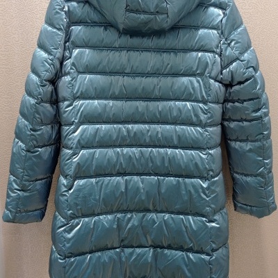 Casaco acolchoado azul pato com capuz pendurado na parede