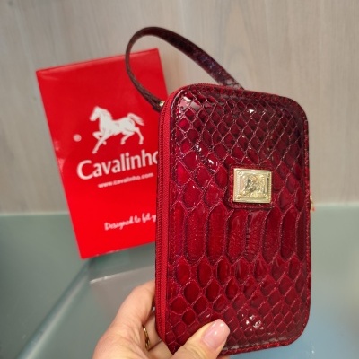 Carteira em couro vermelho com padrão de escamas e placa dourada da marca Cavalinho