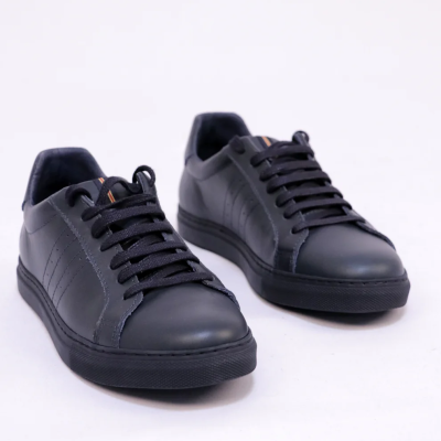 Sapatilhas pretas com atacadores e sola preta em fundo branco