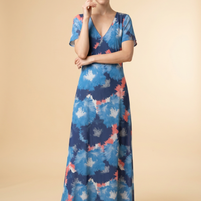 Mulher veste vestido comprido azul com padrão tie-dye e sapatos nude