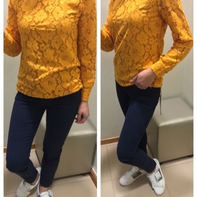 Blusa de renda amarelo mostarda com padrão floral, calças azuis escuras e sapatilhas brancas
