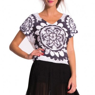 Modelo com blusa preta e branca de padrão floral e saia preta plissada