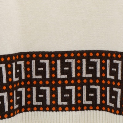 Pormenor de tecido creme com padrão geométrico castanho e detalhes laranja e branco