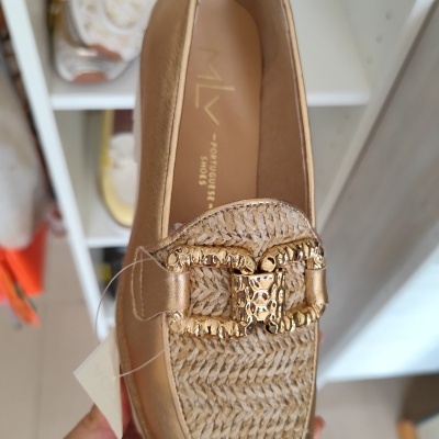Sapato mocassim dourado com tecido trançado e fivela dourada em loja