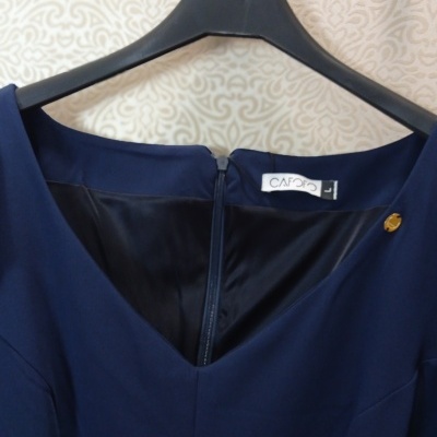 Vestido azul escuro sem mangas pendurado num cabide preto com fecho atrás.