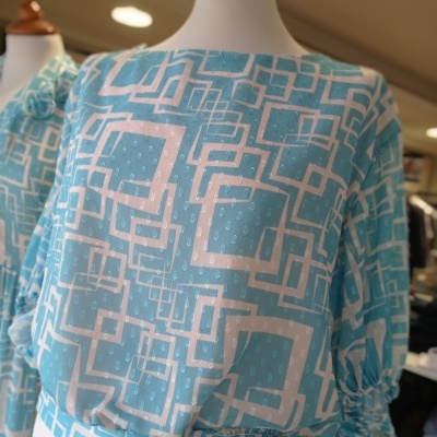 Blusa azul com padrão geométrico branco em manequim