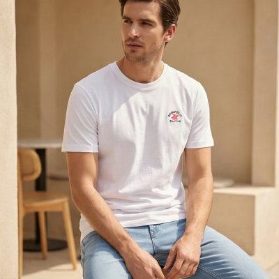 Homem com t-shirt branca e calças de ganga sentado em banco de madeira