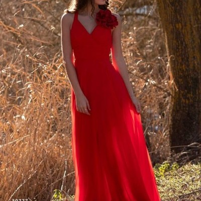 Vestido longo vermelho com detalhe de flor no ombro em ambiente natural