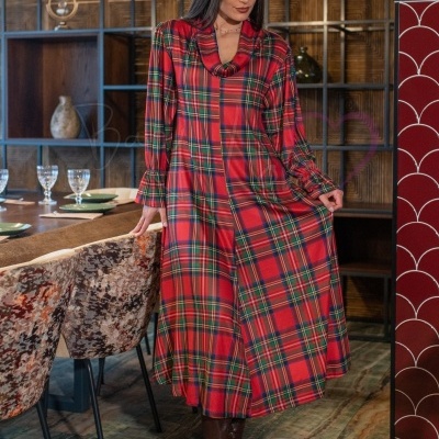 Vestido longo xadrez vermelho e verde com botas castanhas em ambiente interior
