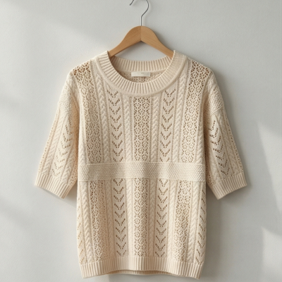 Camisola de malha bege com padrão texturizado pendurada num cabide de madeira