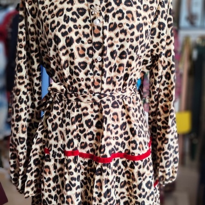 Vestido estampado animal com cinto e detalhes vermelhos num manequim