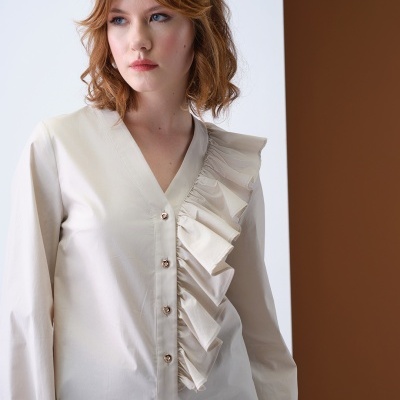 Blusa feminina bege claro com folhos e botões, modelo com cabelo castanho claro