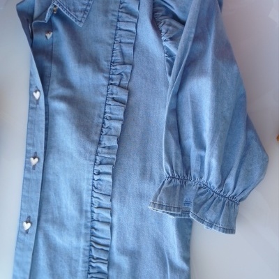 Blusa azul clara com botões de coração e folhos, mangas franzidas, junto a sapato azul claro