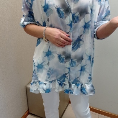 Camisa feminina com padrão de flores azuis e brancas, mangas arregaçadas, barra com babados.