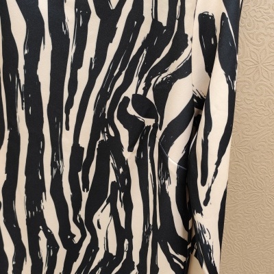 Vestido com padrão preto e branco pendurado contra parede bege texturada